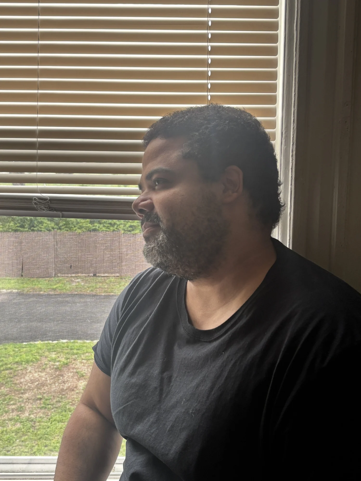 Keelan Watlington seated beside a window on Long Island